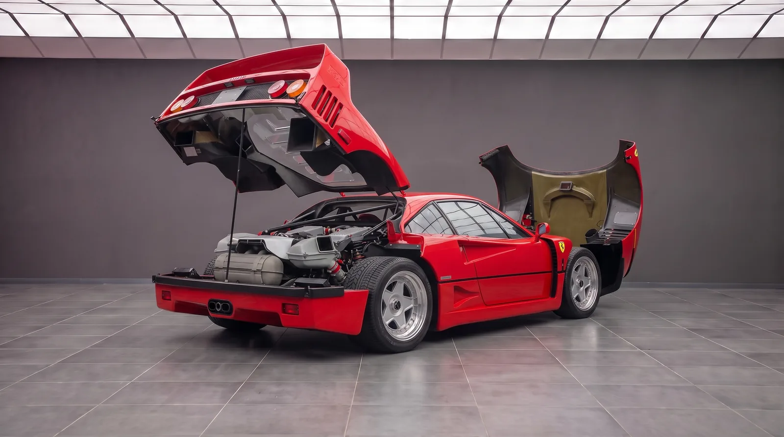 Ferrari F40 with the rear clamshell and front bonnet raised, showing the twin-turbo V8, tubular frame and composite panels