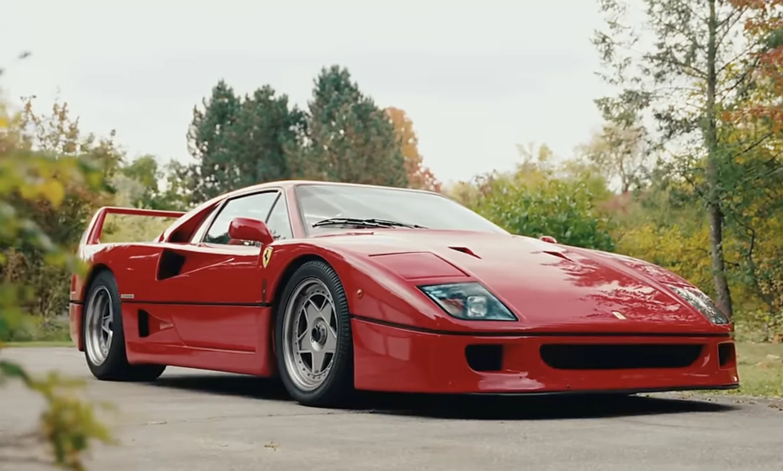 Ferrari F40 front three-quarter view outdoors with pop-up headlight covers closed and the low front splitter in shadow