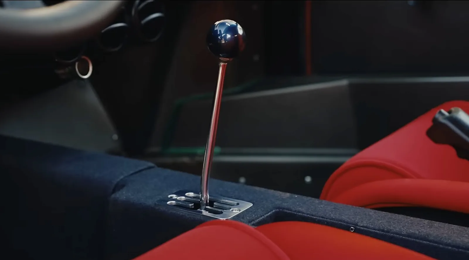 Ferrari F40 cabin detail with the exposed gated five-speed manual shifter, blue trim and red fabric seats