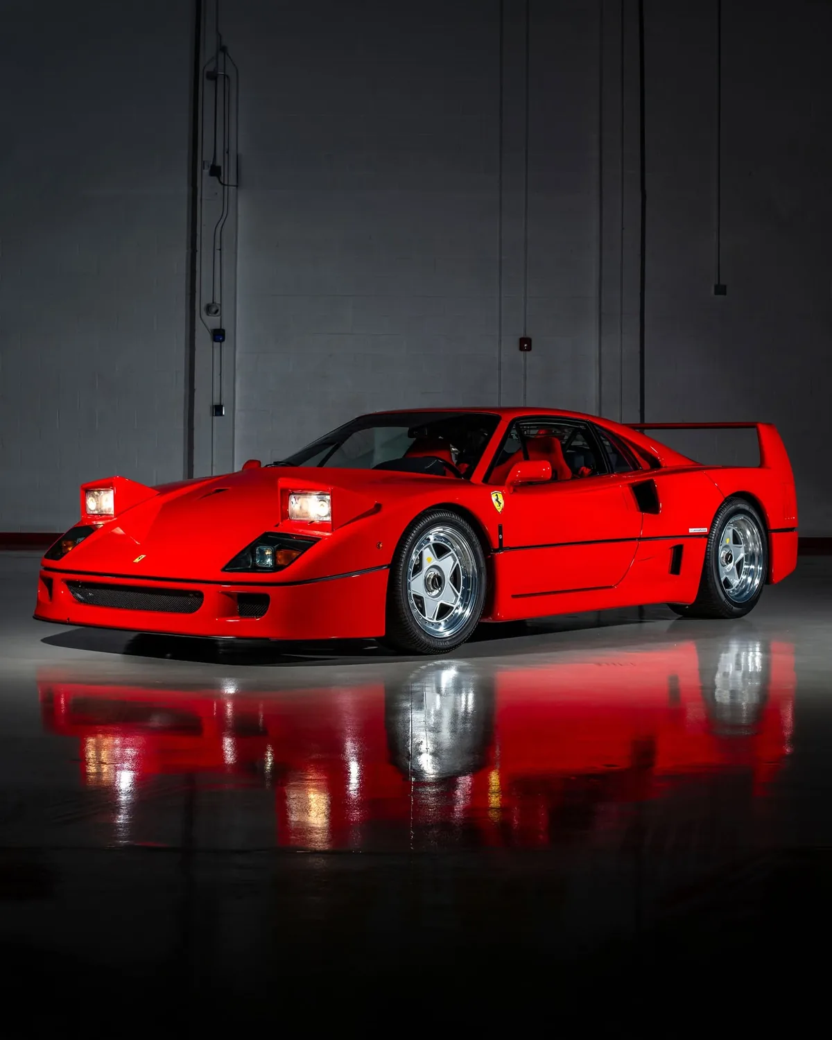 Ferrari F40 studio portrait with pop-up headlights raised, reflected on a polished dark floor