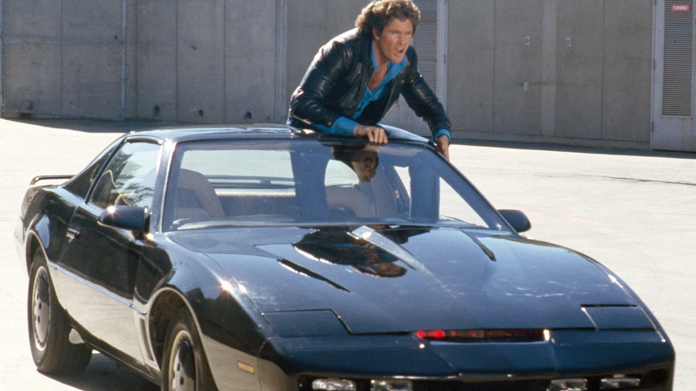 David Hasselhoff as Michael Knight leaning through the T-top of KITT, the black 1982 Pontiac Firebird Trans Am from Knight Rider