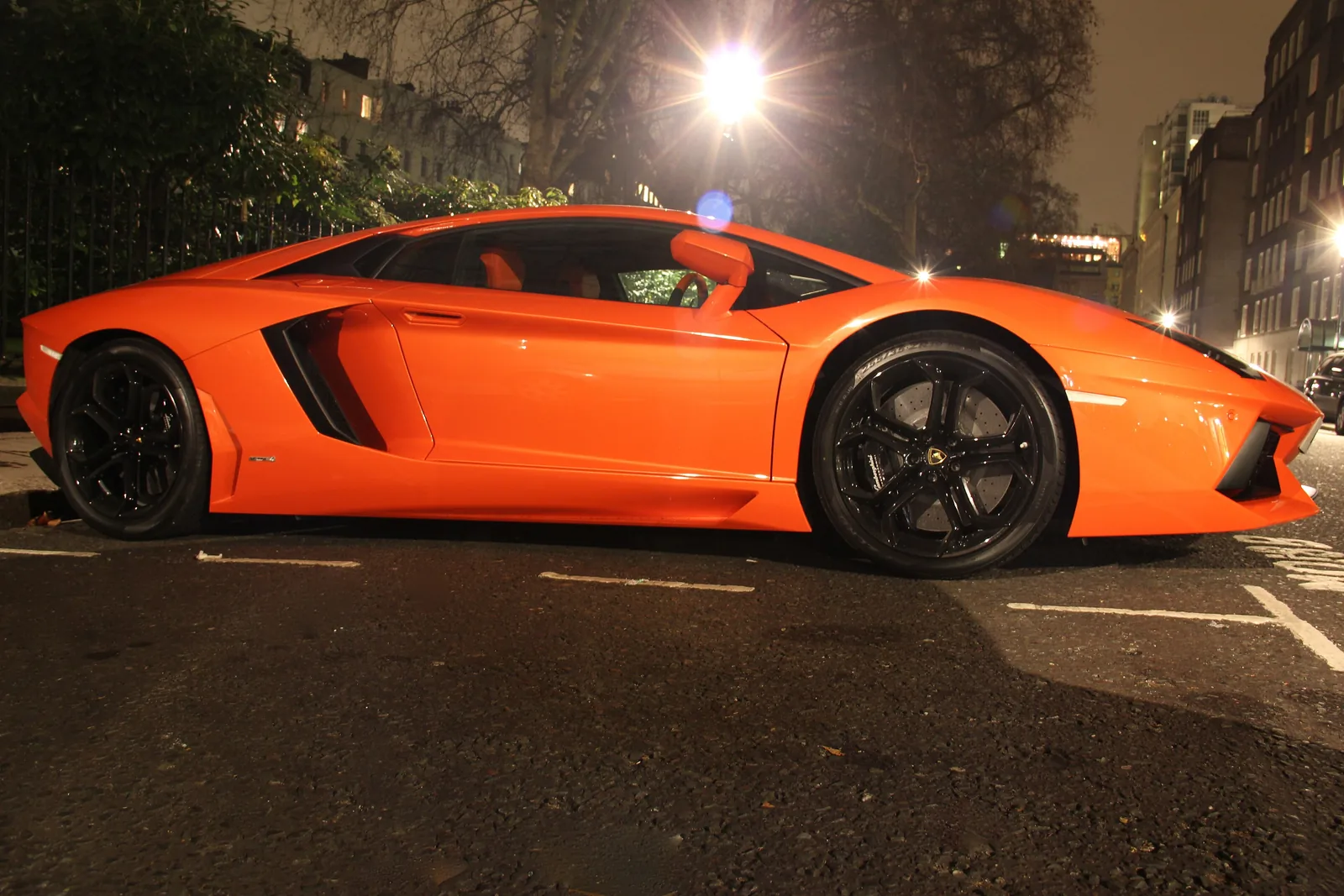 Lamborghini Aventador LP 700-4 coupé side profile in Arancio orange showing the wedge silhouette and scissor-door line