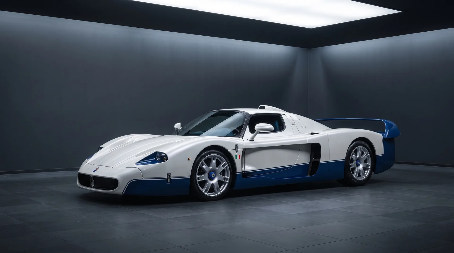 Maserati MC12 Stradale in white and blue, front three-quarter view inside a dark studio