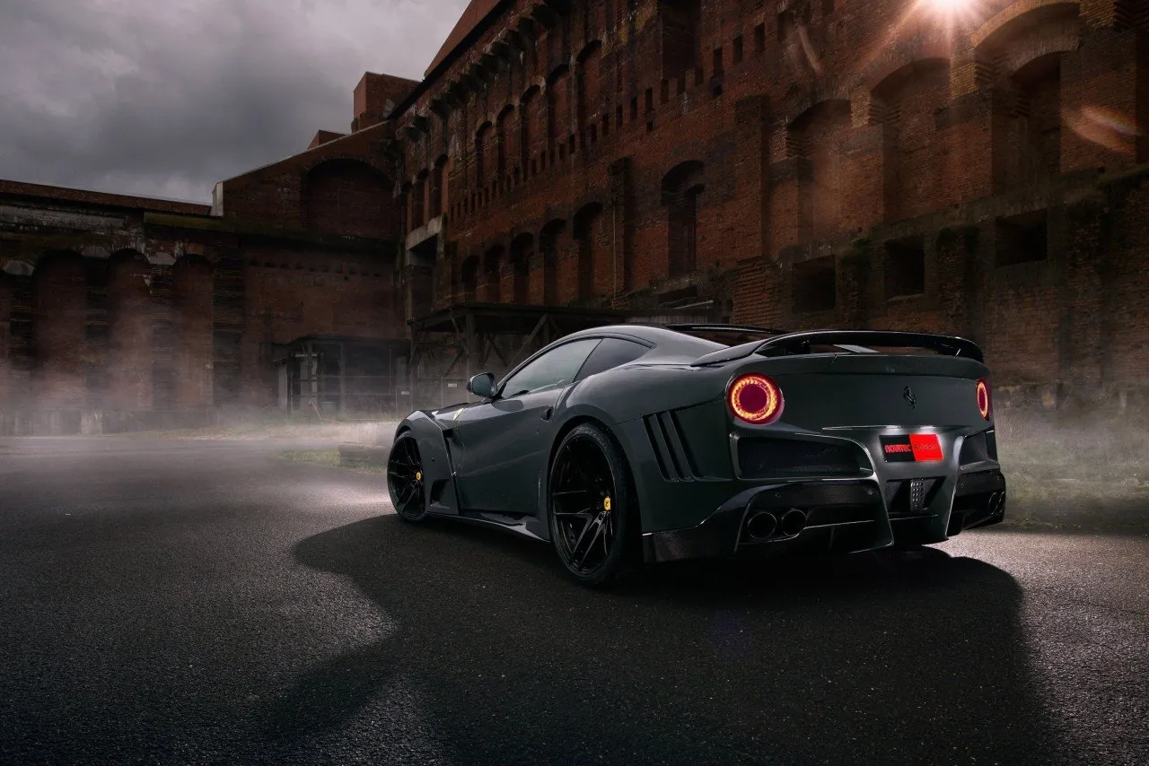 Grey Novitec Ferrari F12 N-Largo S rear view with round tail lights in a dark industrial setting