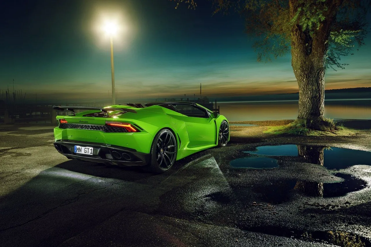 Green Novitec Lamborghini Huracan Spyder N-Largo with roof open at dusk beside a lake