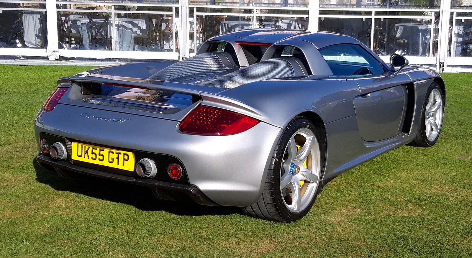 GT Silver Porsche Carrera GT rear three-quarter with carbon-backed seats visible, Carrera GT script, red tail lamps and twin central exhausts