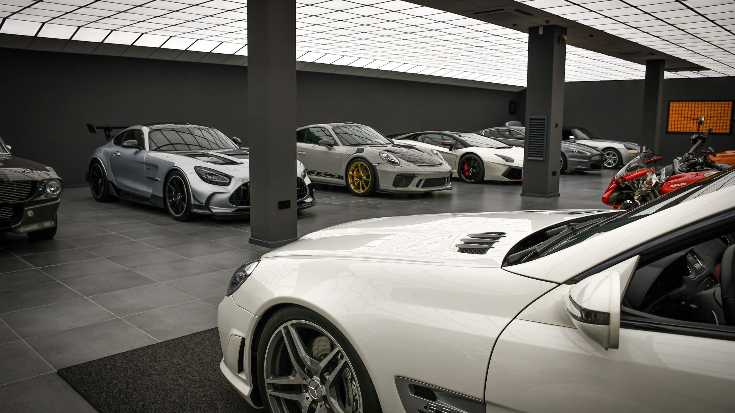 Mercedes-AMG GT Black Series, Porsche 911 GT3 RS, Lamborghini Gallardo and Ducati XDiavel under the LED ceiling at Batman Garage