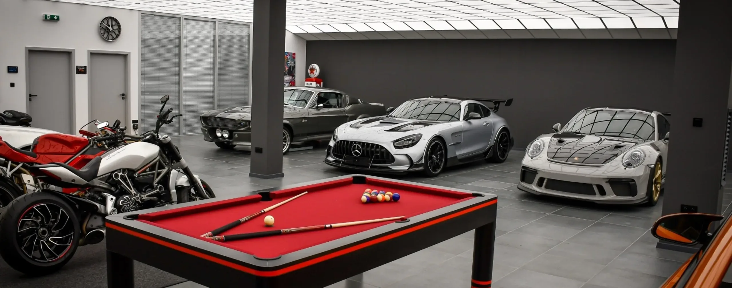 Batman Garage interior — supercars, motorcycles and pool table under the LED ceiling