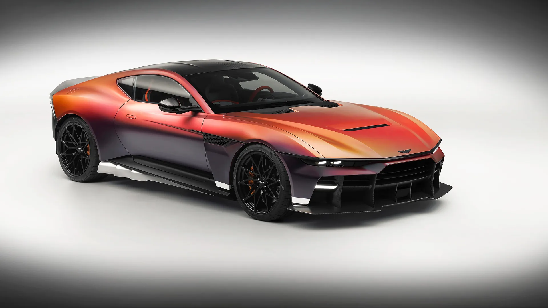 Aston Martin Valen front three-quarter studio view at The Quail Monterey Car Week 2026, Satin Andromeda Red color-shifting paint, black carbon splitter, 21-inch magnesium wheels
