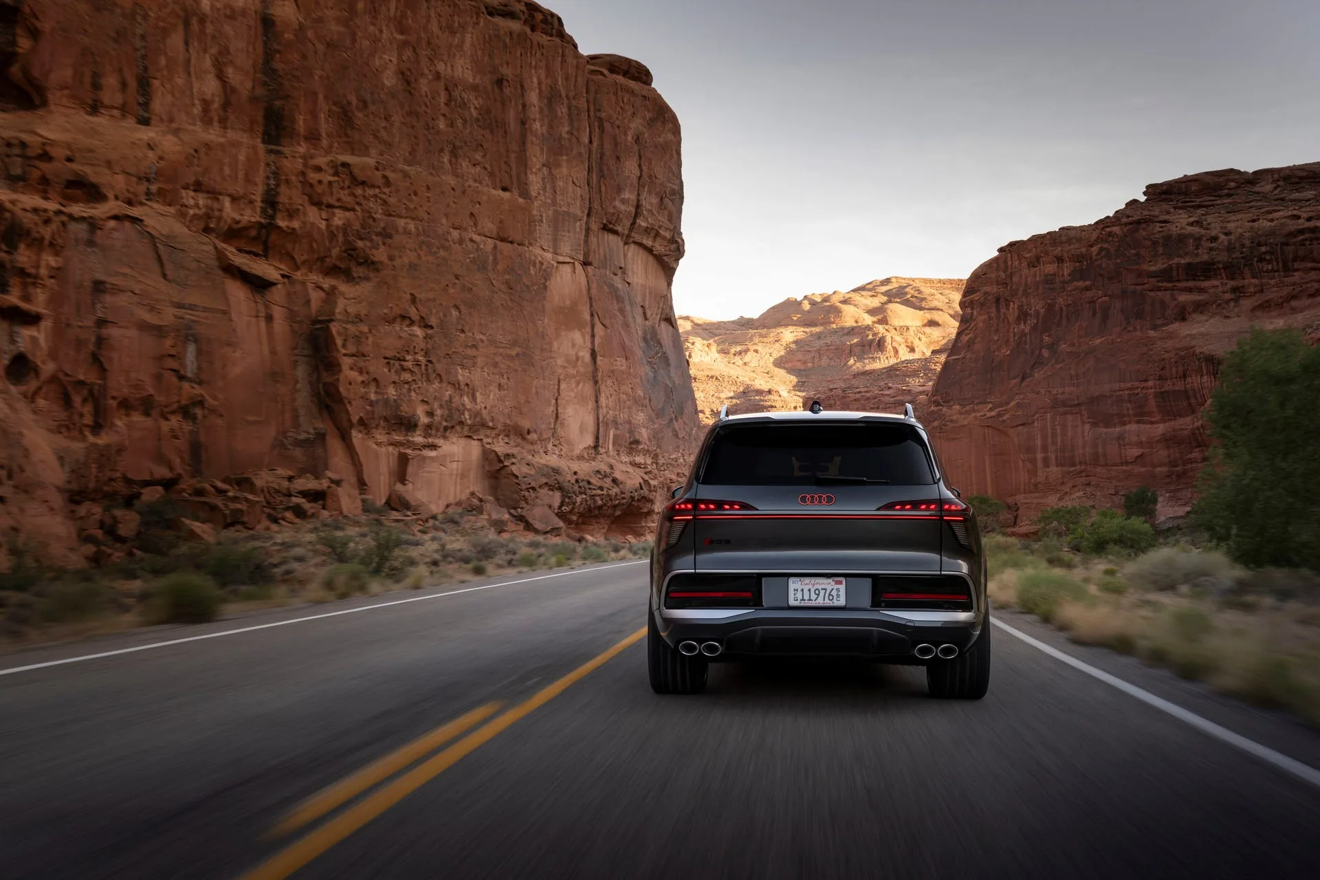 Audi SQ9 rear driving in Utah canyon — full-width OLED taillight bar and quad exhaust tips visible