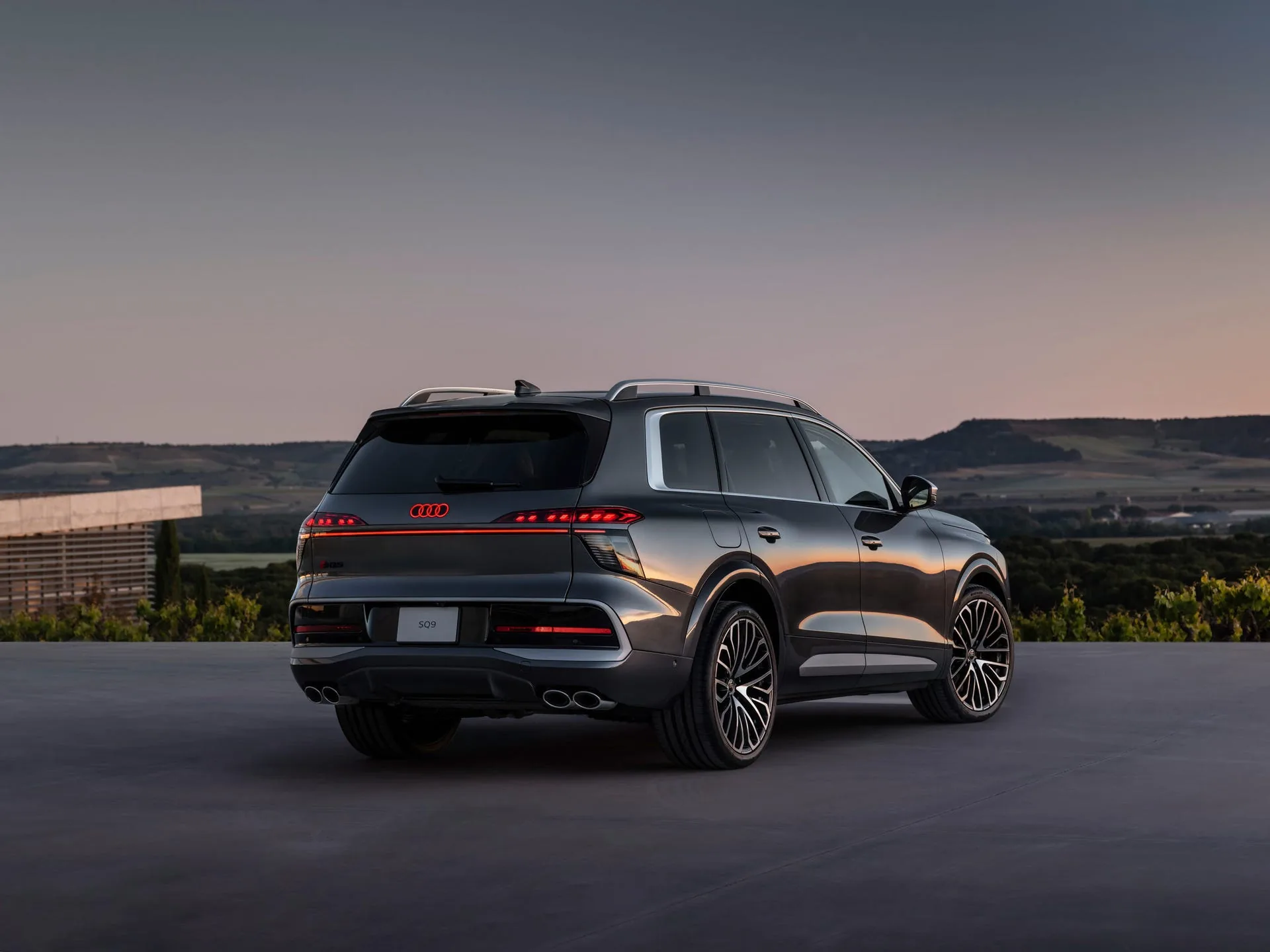 Audi SQ9 rear detail at sunset — curved OLED taillight surface with illuminated Audi rings and switchable light signatures