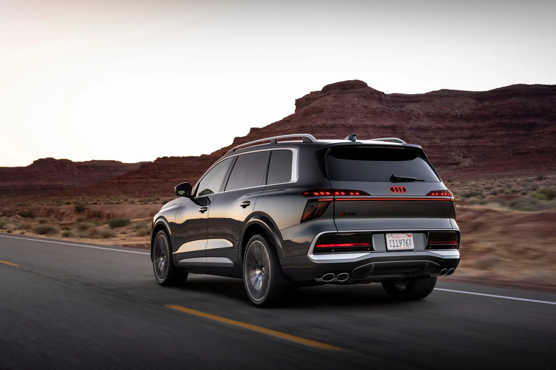Audi SQ9 rear three-quarter in Utah canyon — SQ9 badge, OLED taillight strip and quad exhaust visible