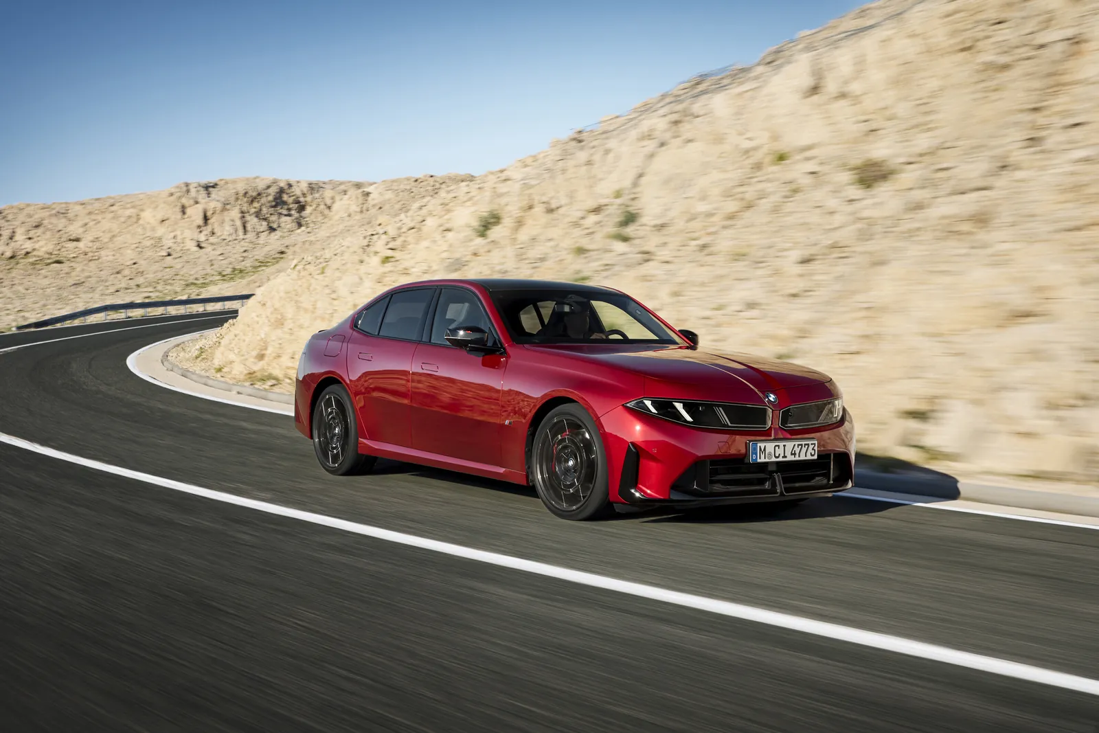 Red BMW M350 xDrive G50 driving on a mountain road