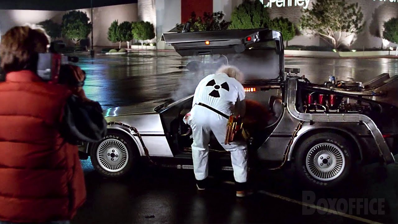 Marty McFly filming Doc Brown beside the DeLorean DMC-12 during the Twin Pines Mall parking-lot test