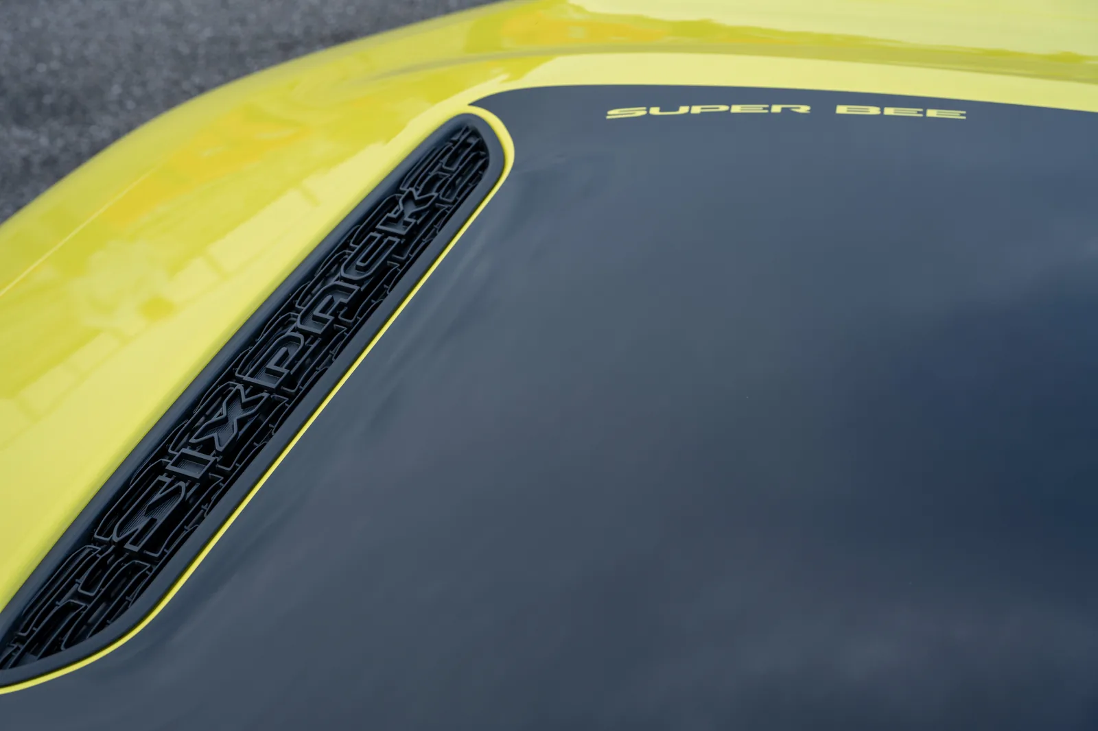 Dodge Charger Super Bee hood close-up &mdash; gloss-black hood patch with Super Bee text and SIXPACK bezel