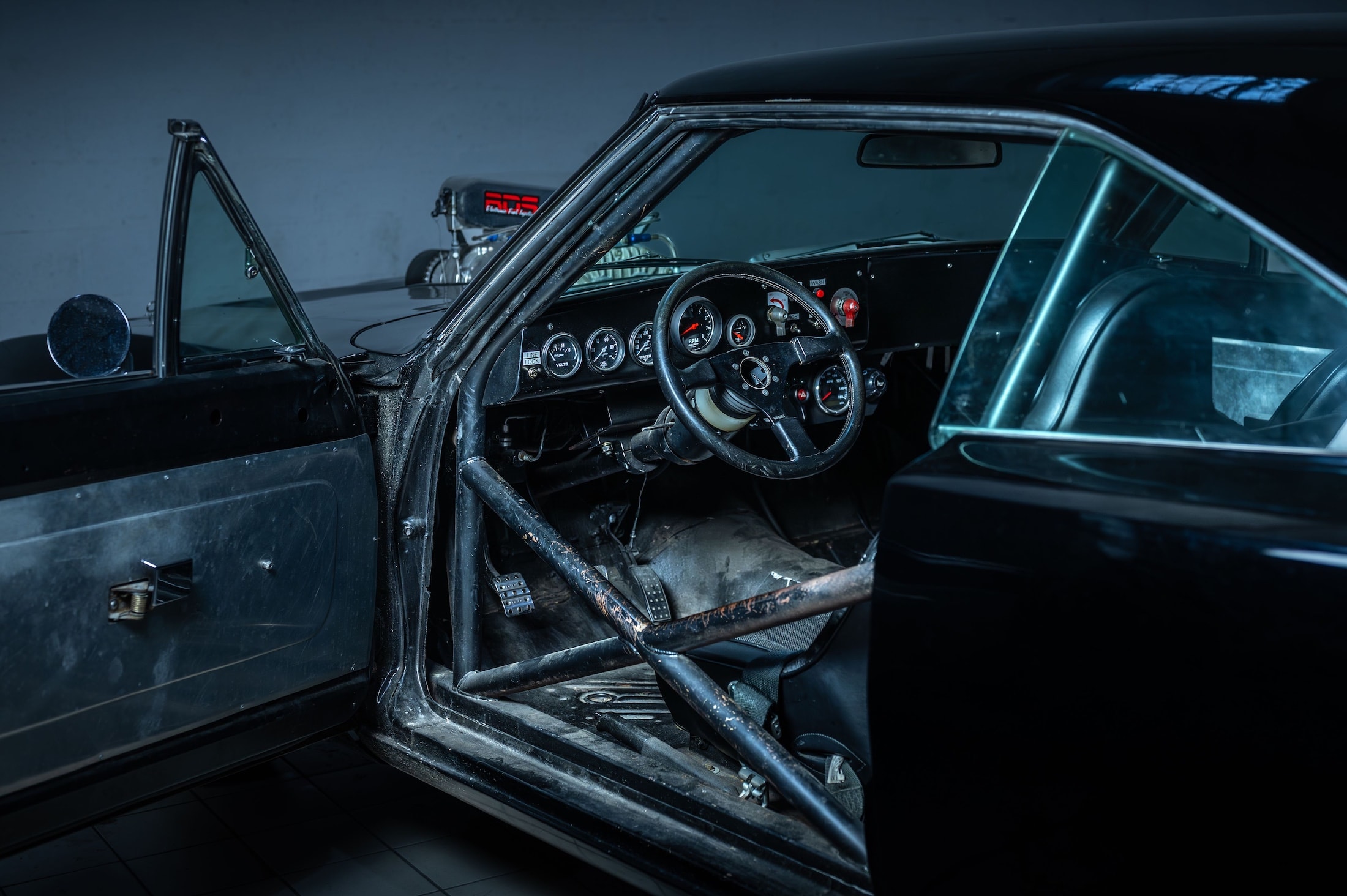 Stripped Dodge Charger stunt-car cabin with roll cage, racing instruments and metal door panels