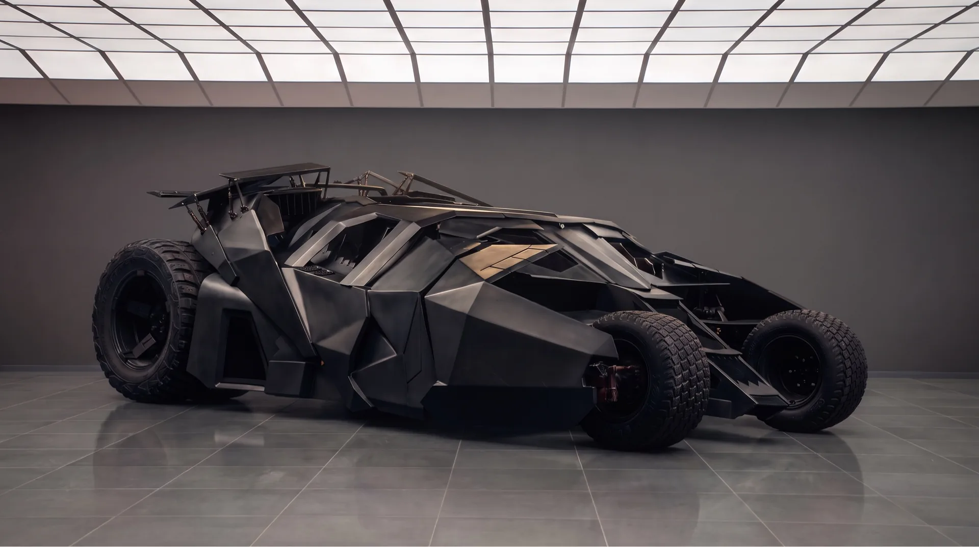 Nolan-era Tumbler Batmobile in a showroom — Batman cars and Batmobile evolution from 1939 to 2026
