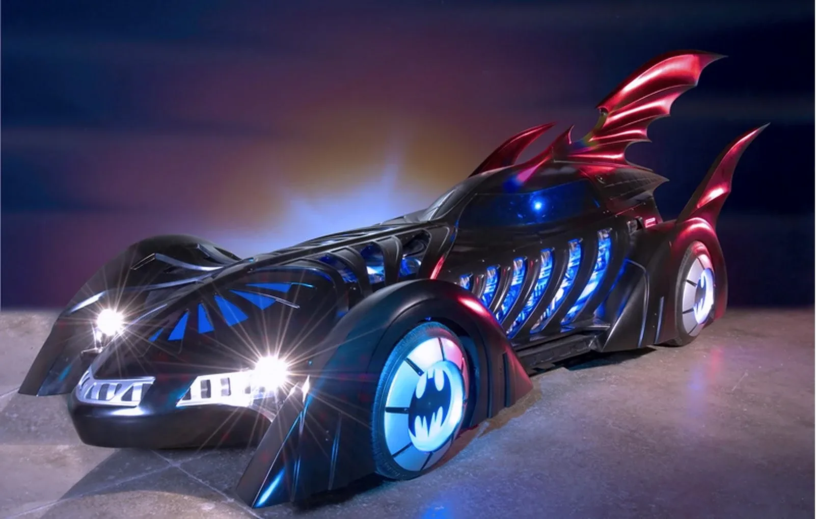 1995 Batman Forever Batmobile designed by Barbara Ling — neon-lit ribbed black bodywork with glowing electric-blue internal piping, exposed engine cell behind the cockpit, raised dragster-style intake and twin curved bat-fins for the Joel Schumacher film