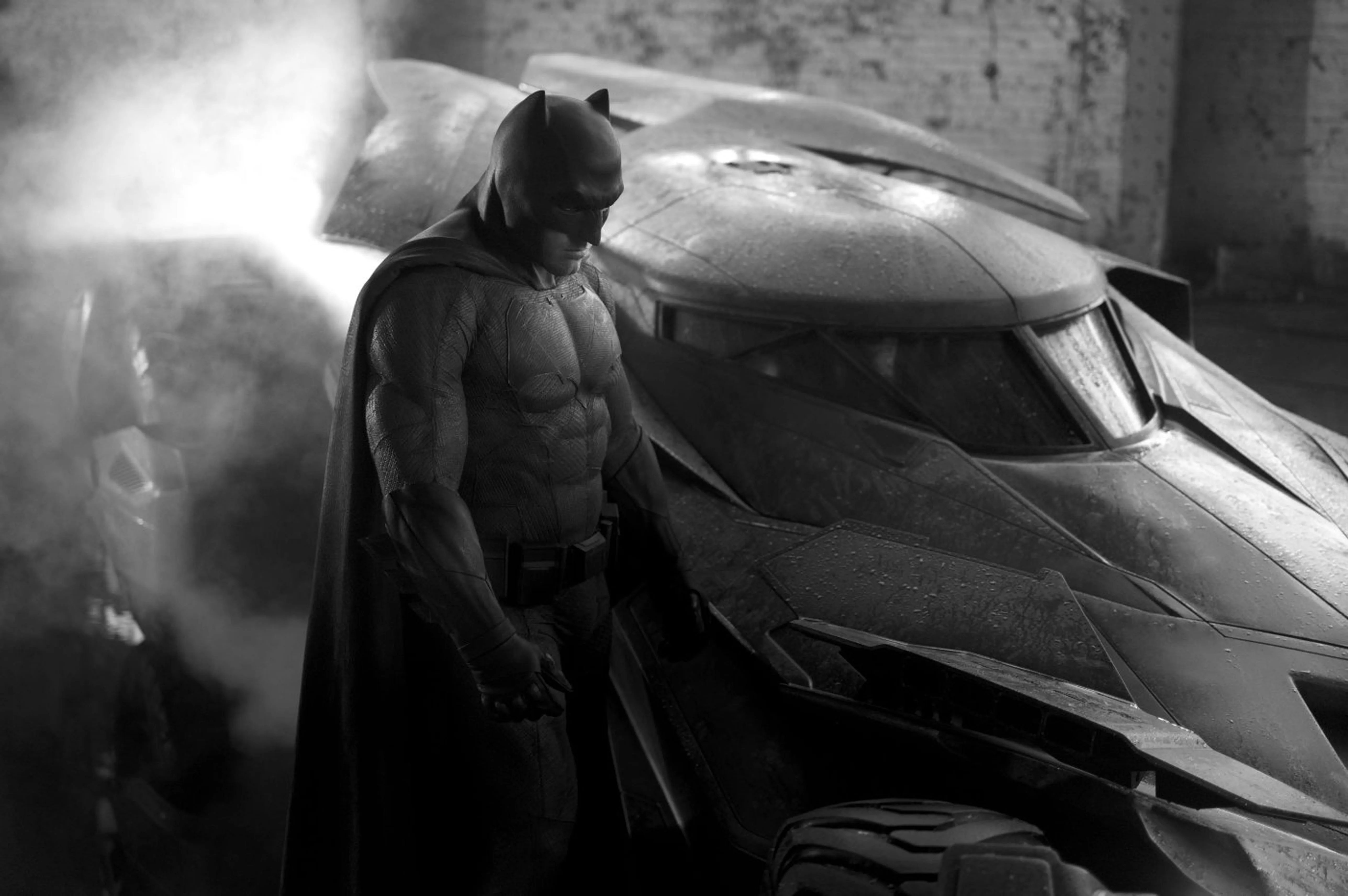 2016 Batman v Superman Batmobile designed by Patrick Tatopoulos — combat-armored matte-black wedge with massive fender-integrated machine guns, exposed roll-cage cockpit, and 20-foot-long aggressive military profile inspired by both the Tumbler and 1989 Anton Furst design