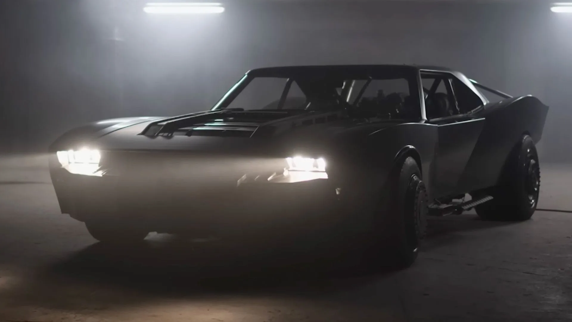 2022 The Batman Batmobile from the Matt Reeves film starring Robert Pattinson — aggressive matte-black DIY muscle car with twin jet exhaust, exposed Hemi V8 engine, raised wheel arches, roll cage, and 1968-1970 Dodge Charger inspired silhouette