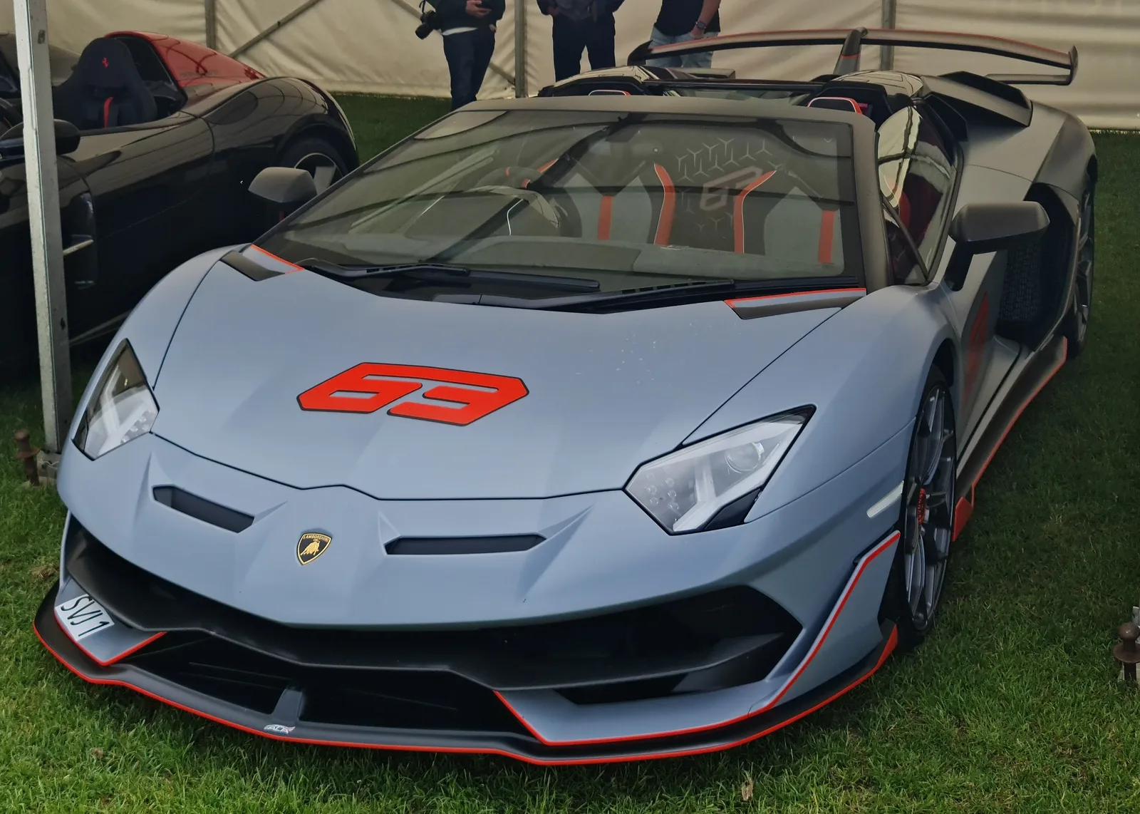 Lamborghini Aventador SVJ 63 Roadster in grey with red 63 graphics on the nose, front three-quarter view showing the carbon splitter and exposed carbon-fibre bodywork
