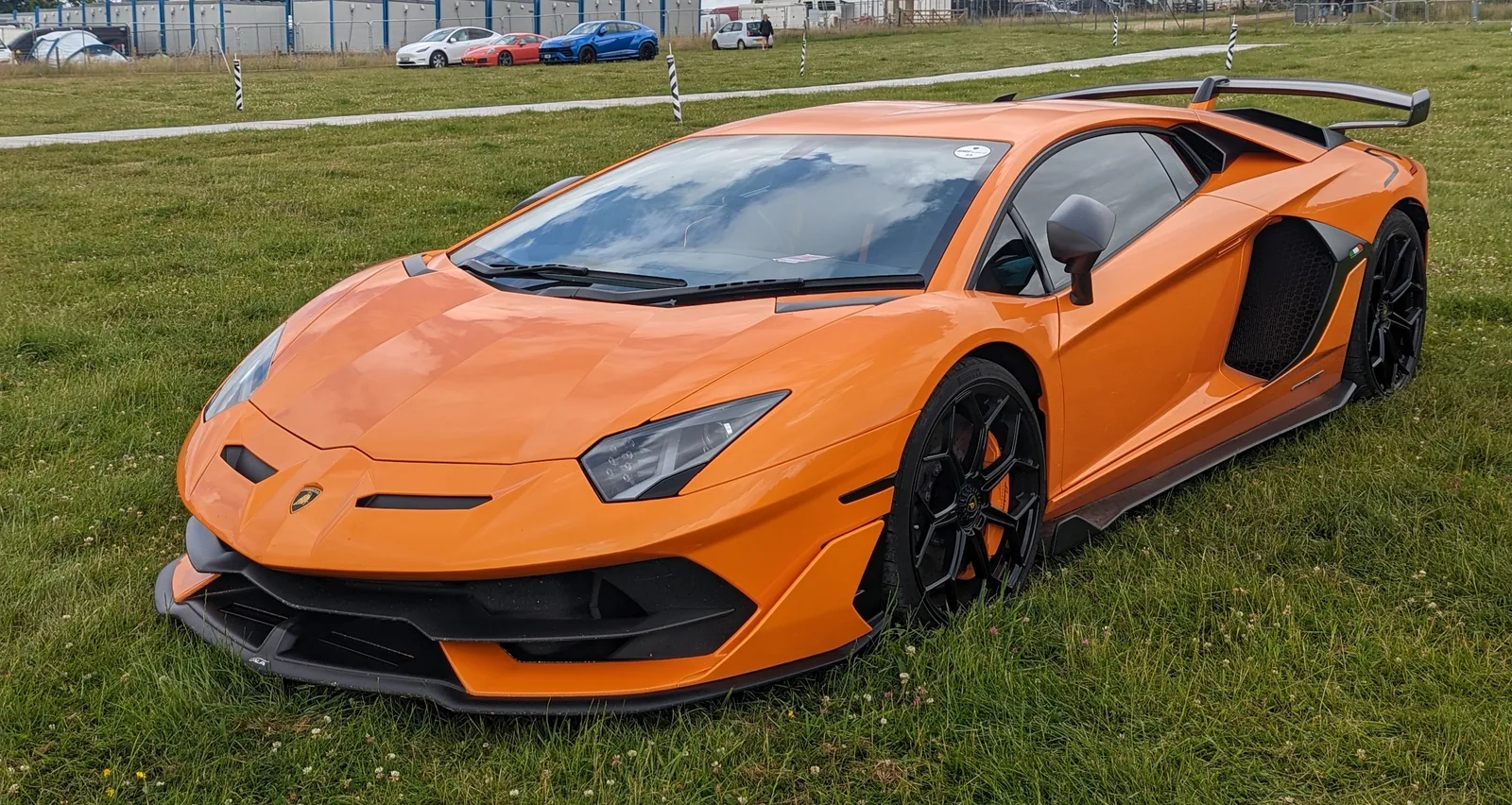 Lamborghini Aventador SVJ in orange, front three-quarter view showing the ALA 2.0 carbon front splitter, hexagonal side intakes and forged wheels