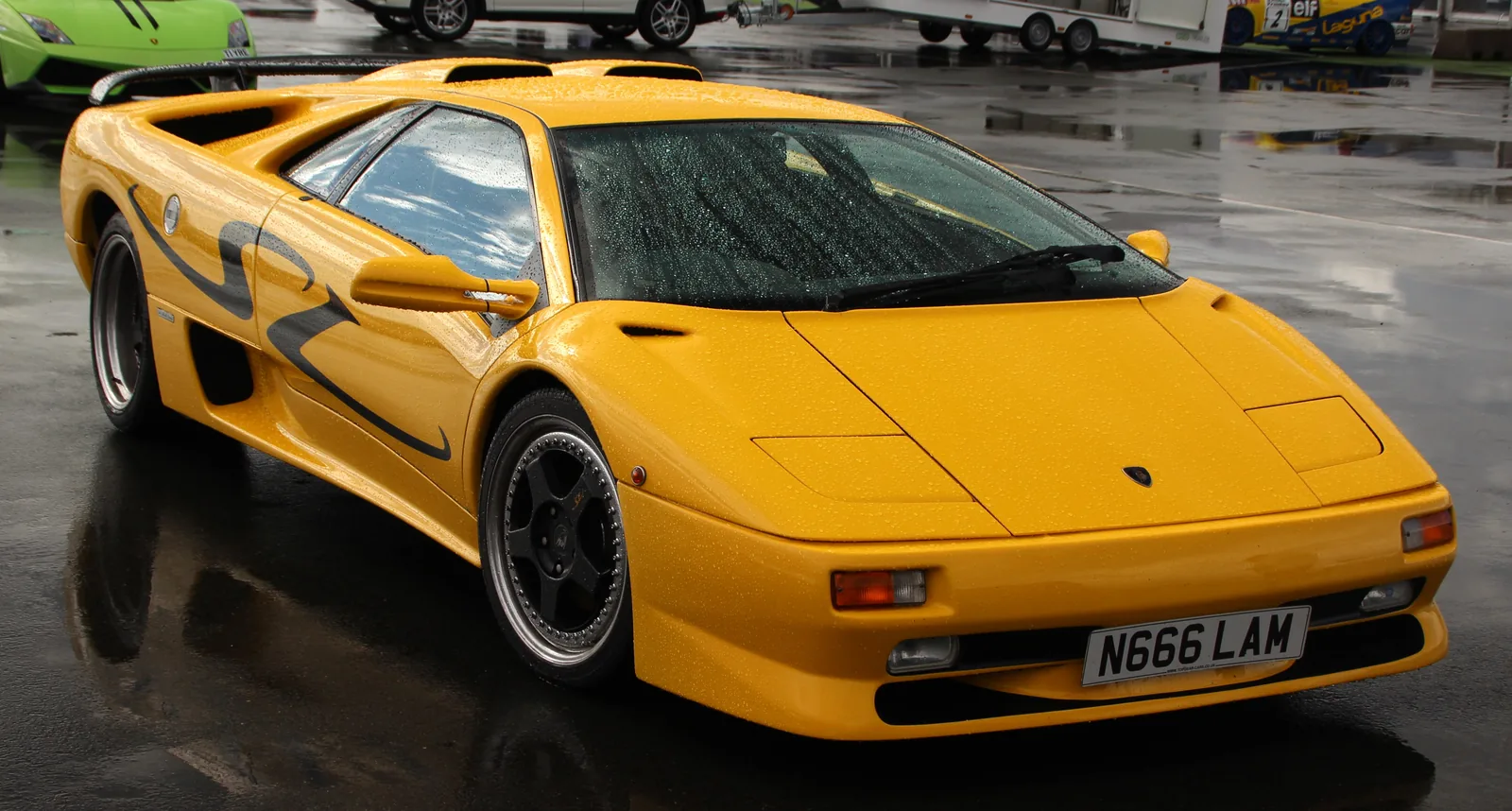 Lamborghini Diablo SV in yellow, front three-quarter view showing the black SV side graphic, dual round fog lamps and adjustable rear wing of the rear-wheel-drive Super Veloce