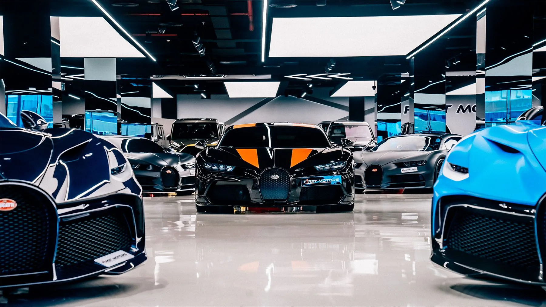 F1rst Motors Dubai showroom Bugatti lineup — Divo, Chiron Sport 300+, Chiron and Chiron Pur Sport parked in formation under gold ceiling accents inside the Sheikh Zayed Road hypercar dealership