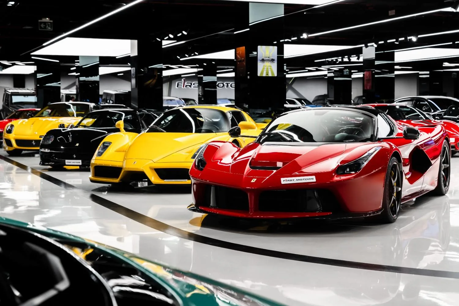 Ferrari V12 heritage lineup at F1rst Motors Dubai showing red LaFerrari, yellow Enzo, silver F50 and black 599 GTO parked side by side