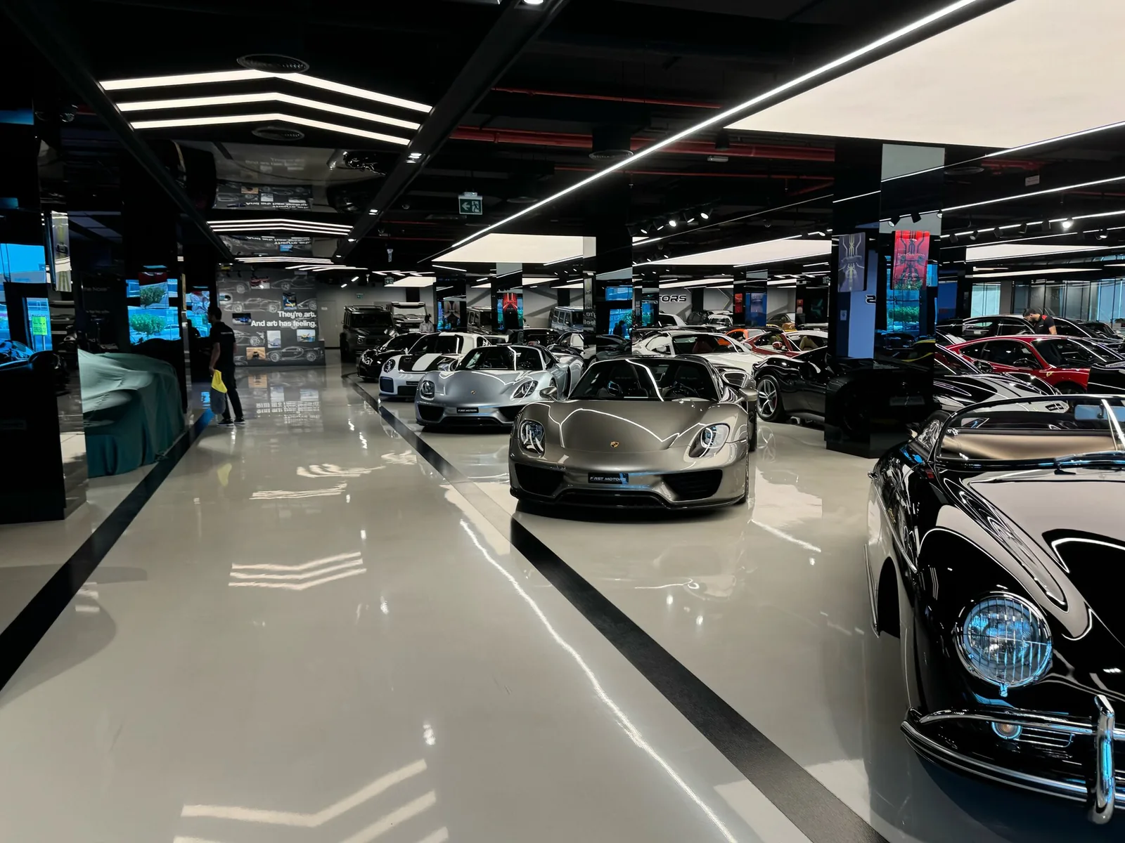Porsche 918 Spyder alongside a classic Porsche 356 inside F1rst Motors Dubai showing the mix of modern and heritage Porsche models