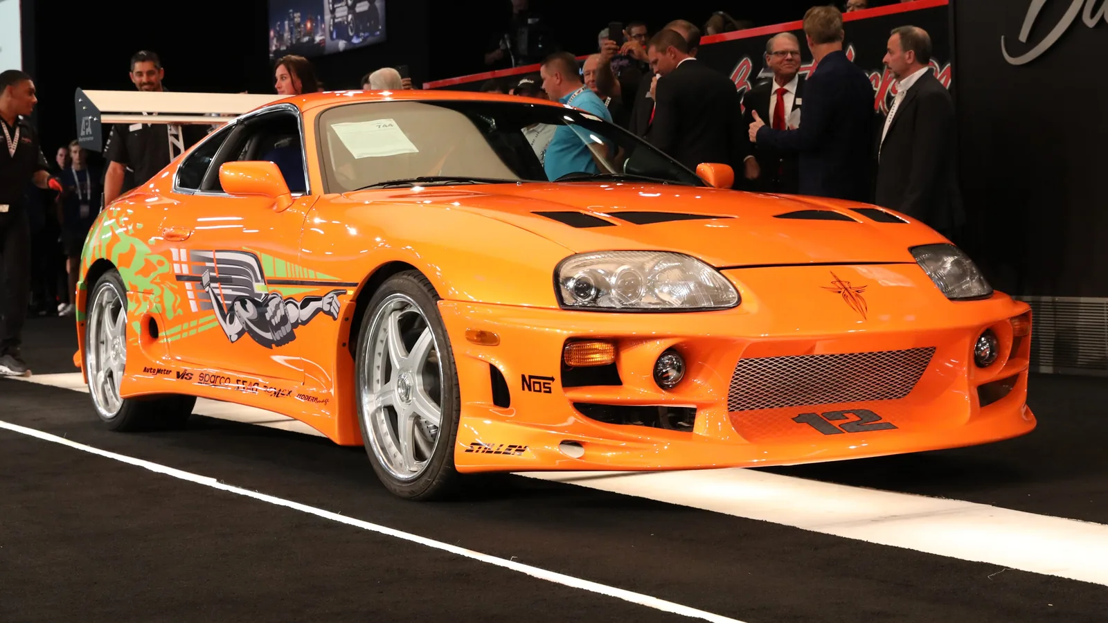 Side profile of the orange Supra showing its Nuclear Gladiator graphics
