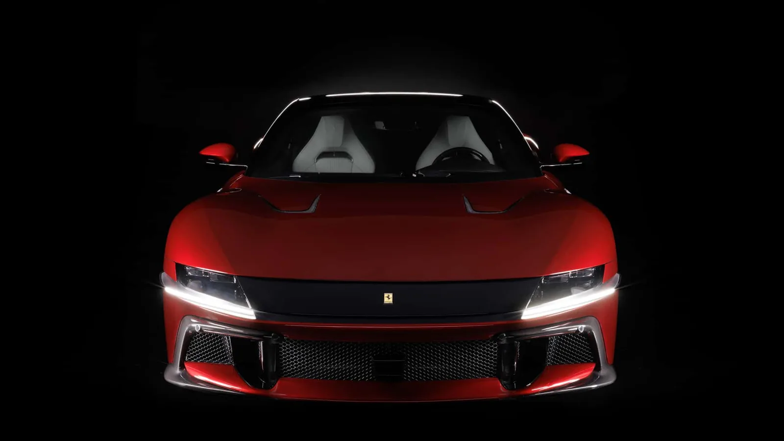 Ferrari 12Cilindri Manuale front head-on studio shot — full-width light bar, prancing horse badge, dark background