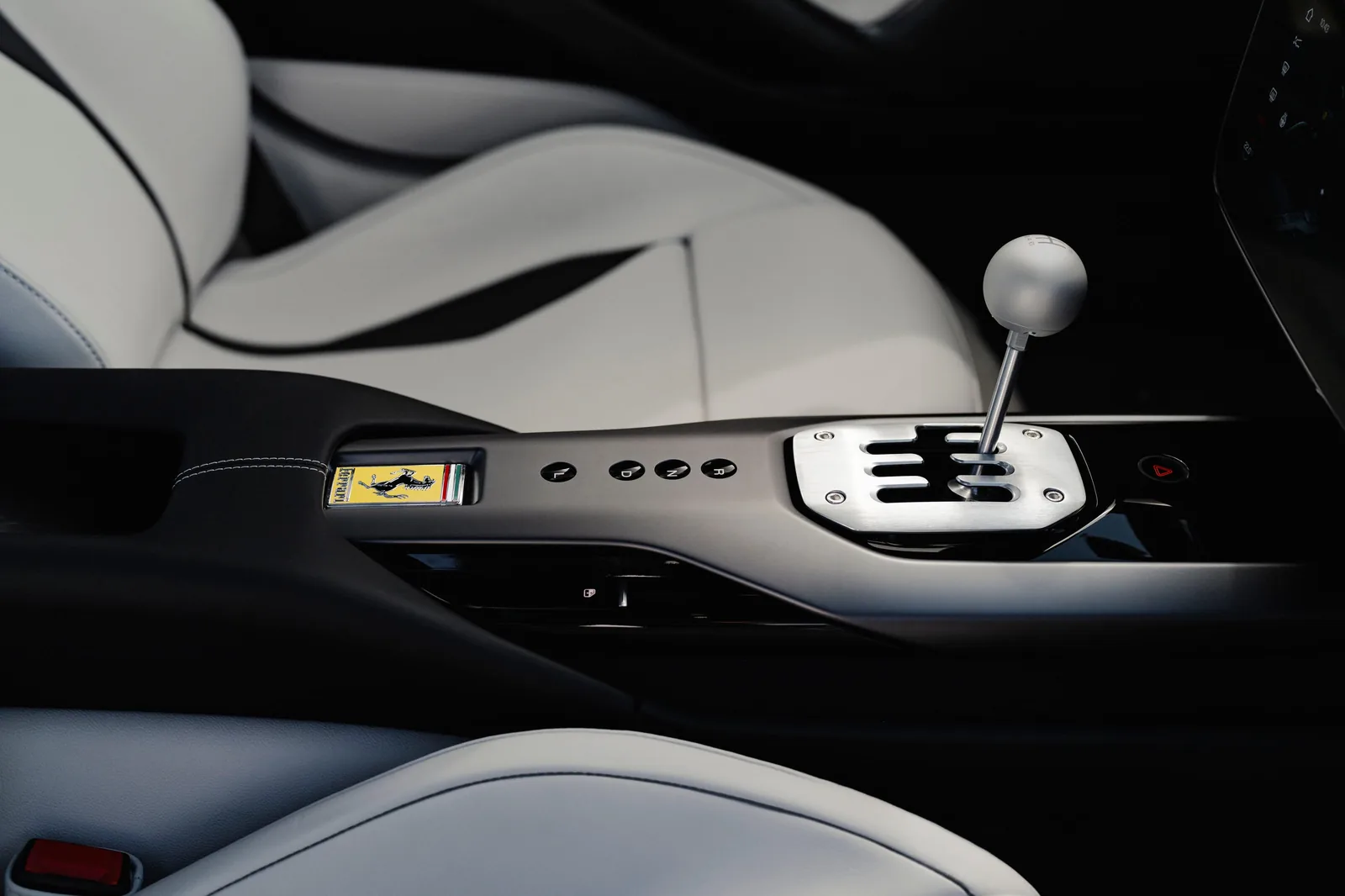 Ferrari 12Cilindri Manuale gated shifter side view — brushed aluminium gate with matte spherical knob between white leather seats