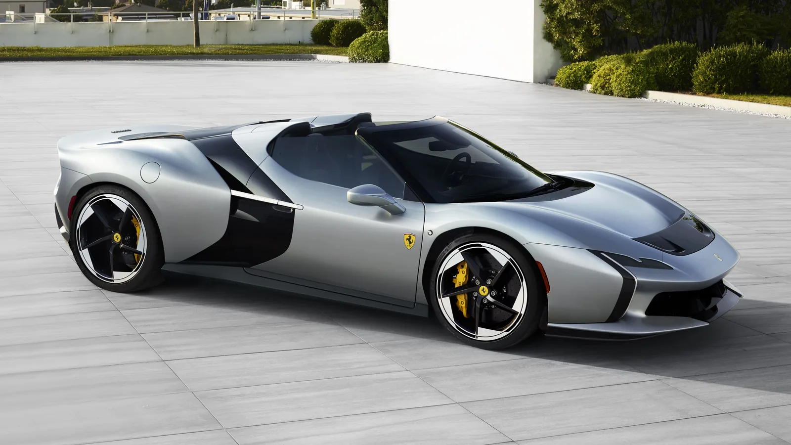 Ferrari HC25 front three-quarter in late afternoon light — vertically oriented daytime running lights inspired by the Ferrari F80, deep front splitter, yellow prancing horse badge and twin air intakes either side of the nose