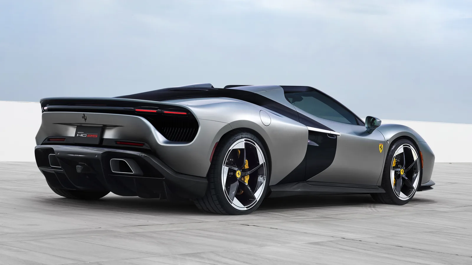 Ferrari HC25 rear three-quarter view in Matte Moonlight Grey — split tail-light signature, the integrated HC25 lettering on the rear panel, glossy-black engine cover ribbon and exposed black diffuser