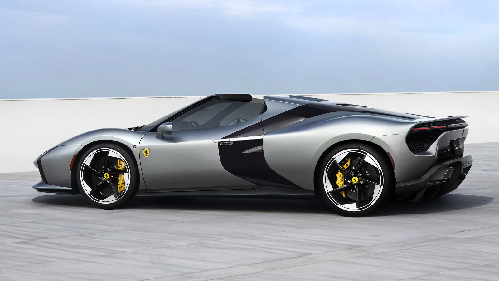 Ferrari HC25 side profile in Matte Moonlight Grey — clean wedge silhouette, dramatic forward-leaning black ribbon, yellow Brembo carbon-ceramic calipers behind diamond-finished five-spoke wheels