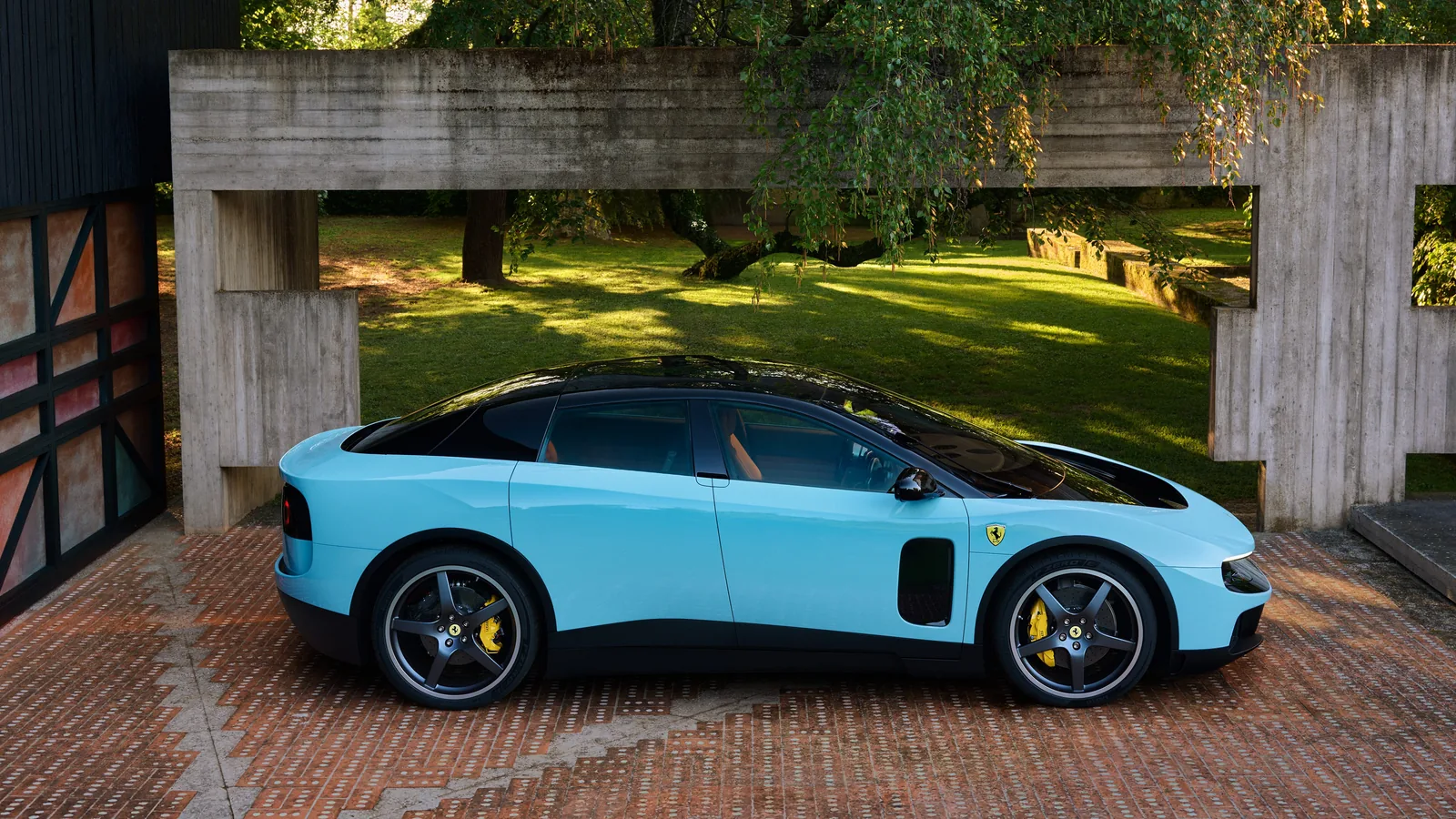 Ferrari Luce front view in Azzurro La Plata light blue paint — the controversial 2027 Ferrari EV designed by LoveFrom showing the headlight-free front fascia, glass roof and clean horizontal proportions criticized for resembling Apple product design