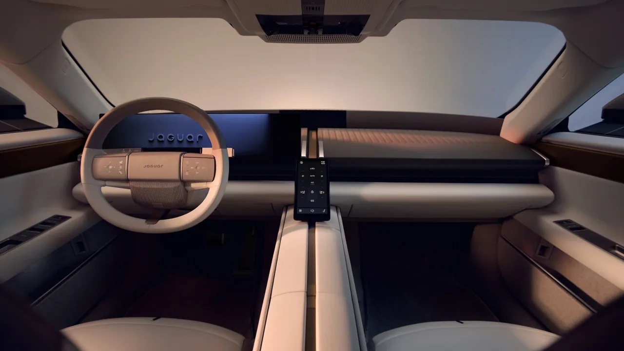 Jaguar Type 01 interior with two-spoke steering wheel, wide digital display, small vertical touchscreen and brass-finished central spine