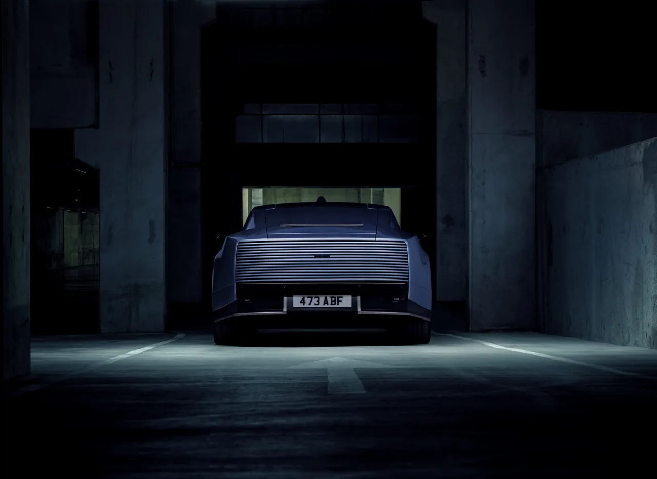 Rear of the blue Jaguar Type 01 with full-width ribbed panel and no rear window, in a dark car park