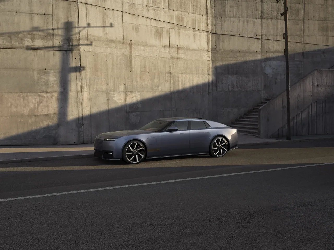 Blue-grey Jaguar Type 01 parked on a street in front of a concrete wall, side view