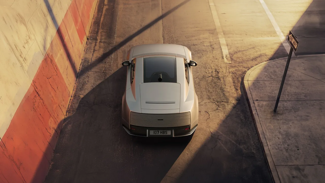 Silver Jaguar Type 01 seen from above on a sunlit street, showing the glass roof and ribbed tail