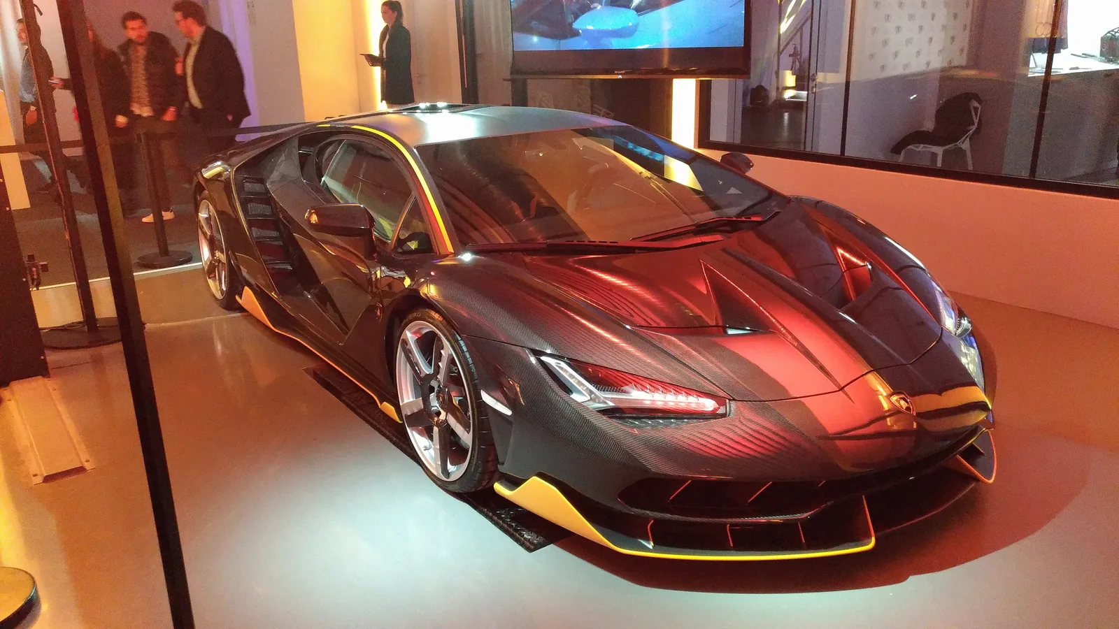 Lamborghini Centenario coupe in dark red with gold accents displayed in a Lamborghini showroom