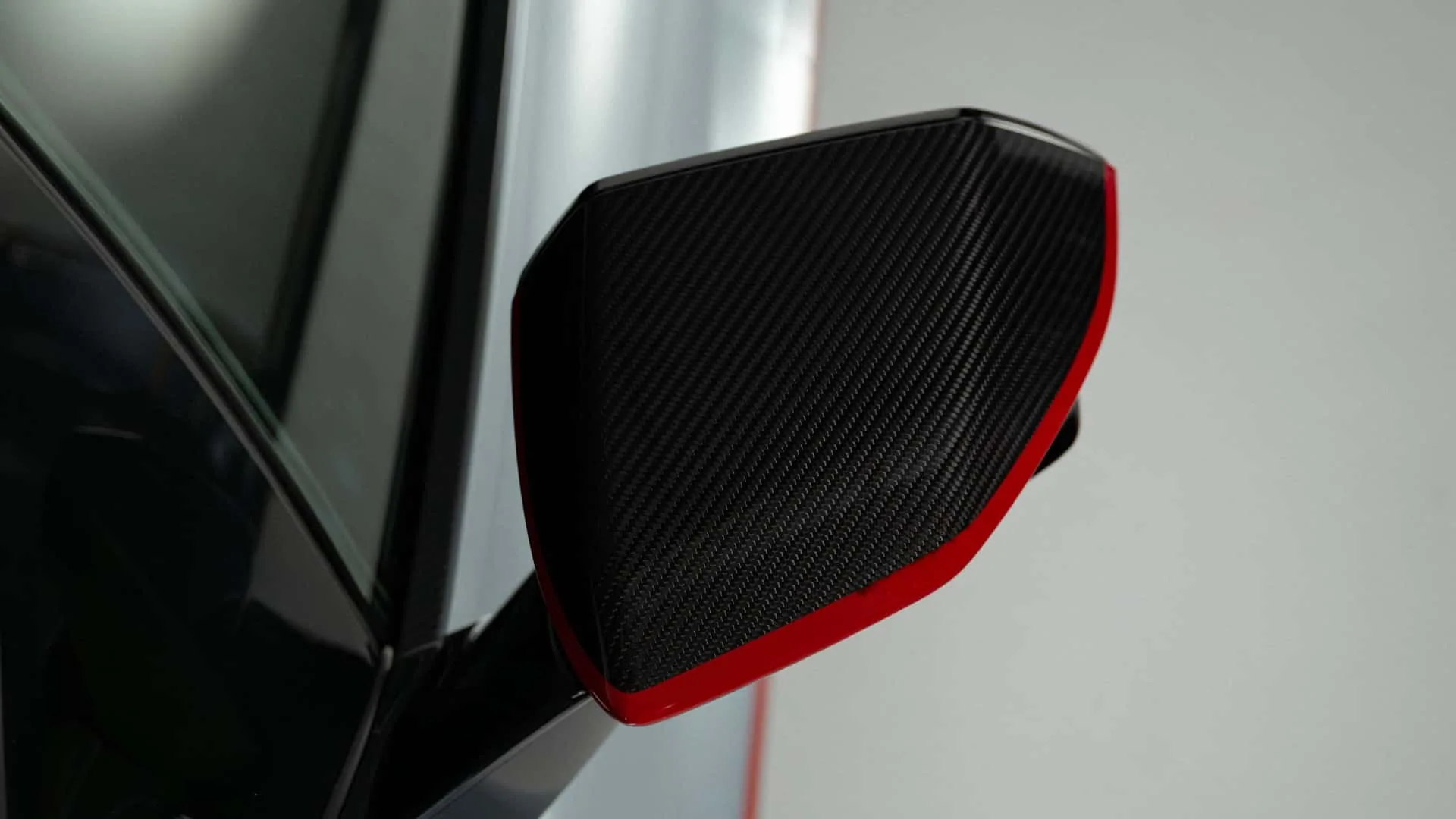 Lamborghini Revuelto SV carbon fibre side mirror close-up with red pinstripe accent