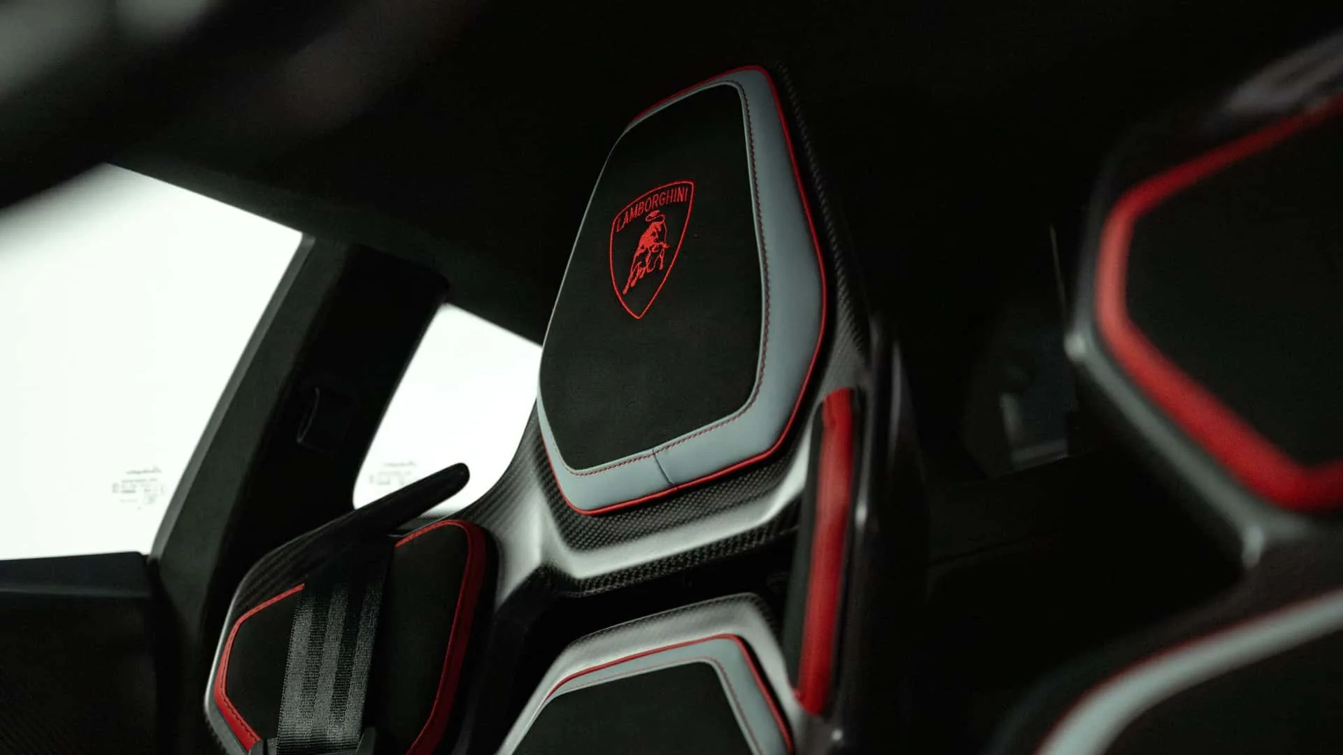 Lamborghini Revuelto SV seat back detail with embossed Lamborghini shield in red thread on Alcantara and carbon fibre