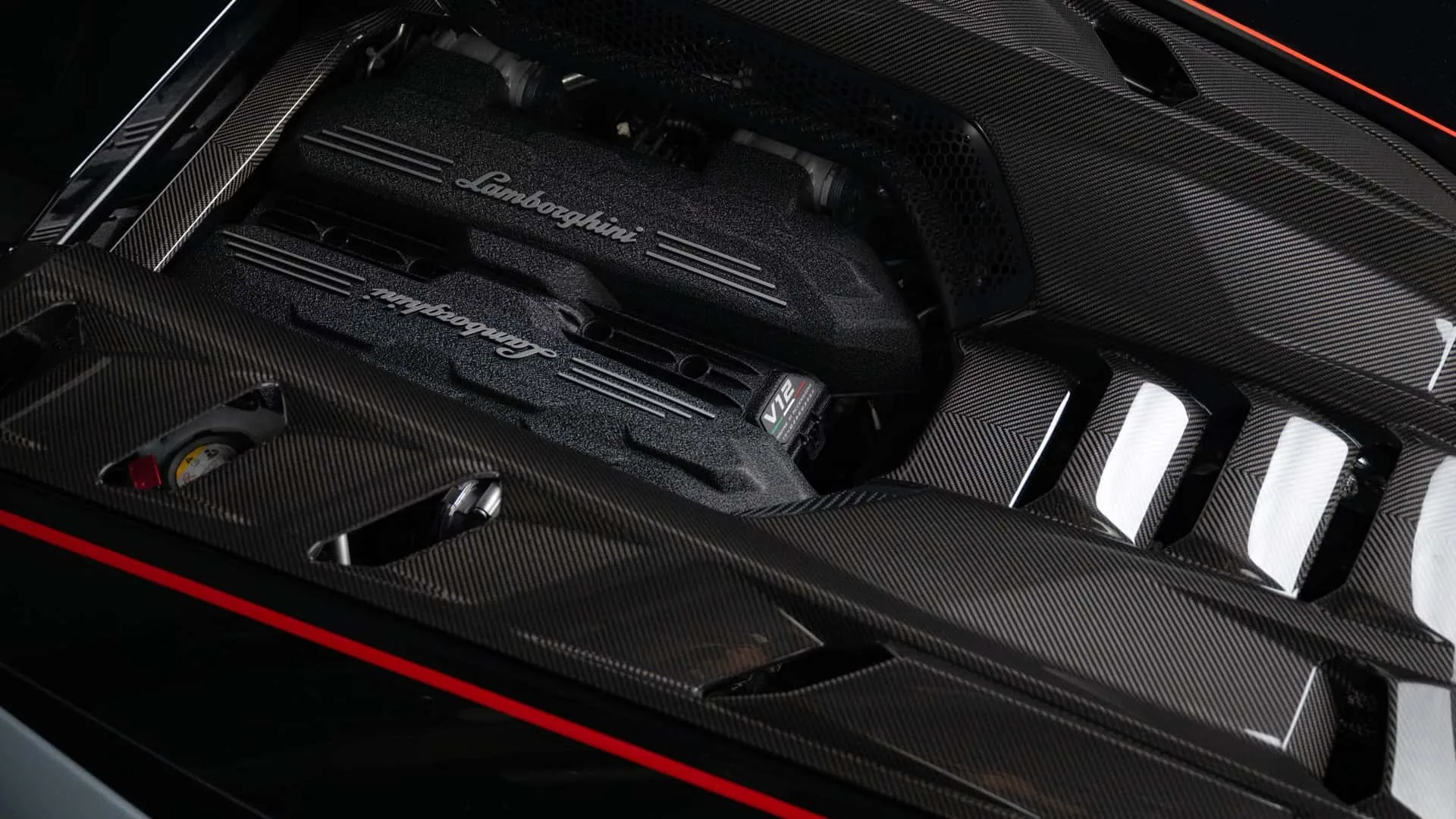 Lamborghini Revuelto SV V12 engine bay showing carbon fibre air intake covers with Lamborghini script and V12 badge