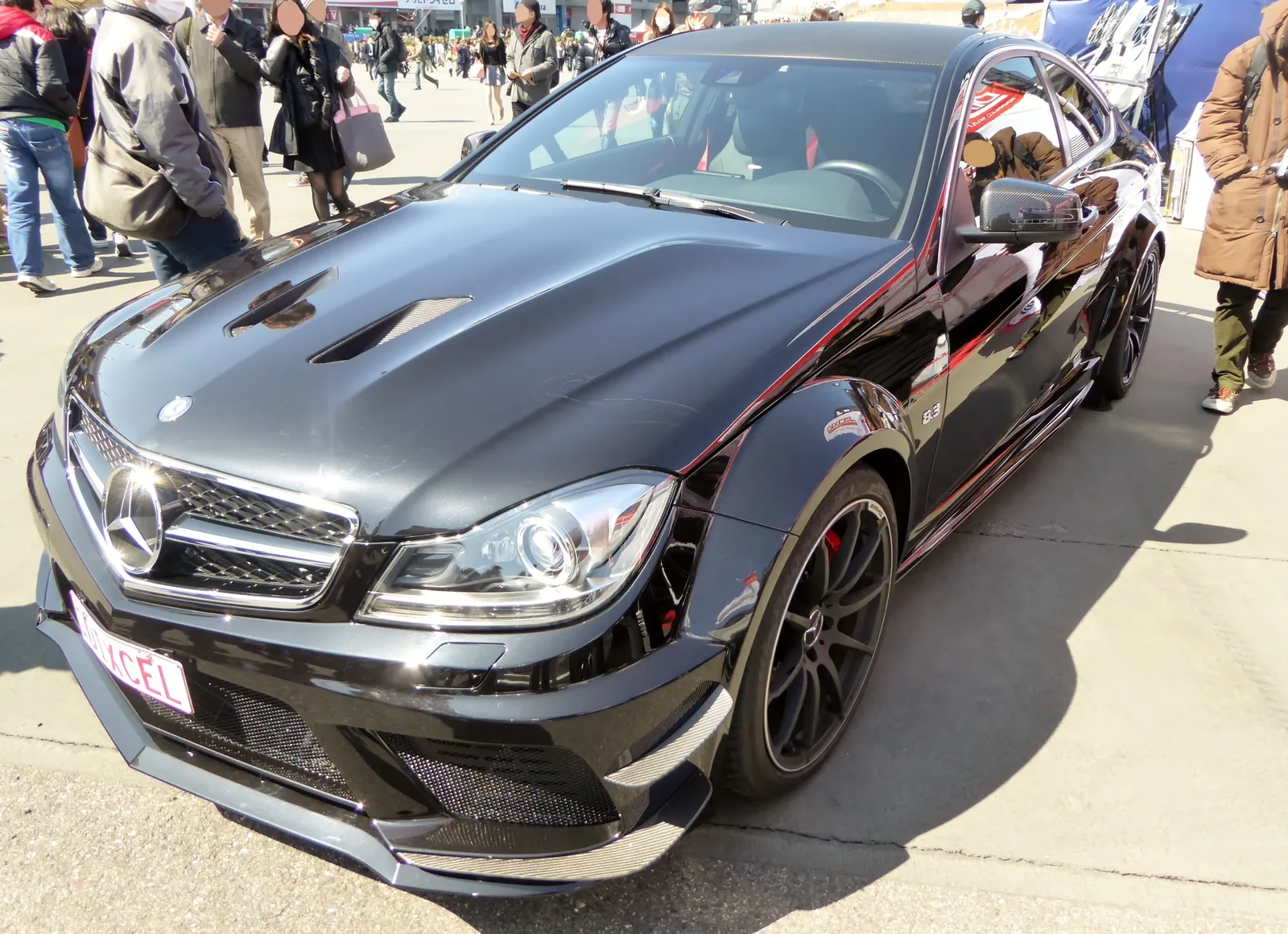 Black Mercedes-Benz C 63 AMG Coupe Black Series at an outdoor motor show, front three-quarter view