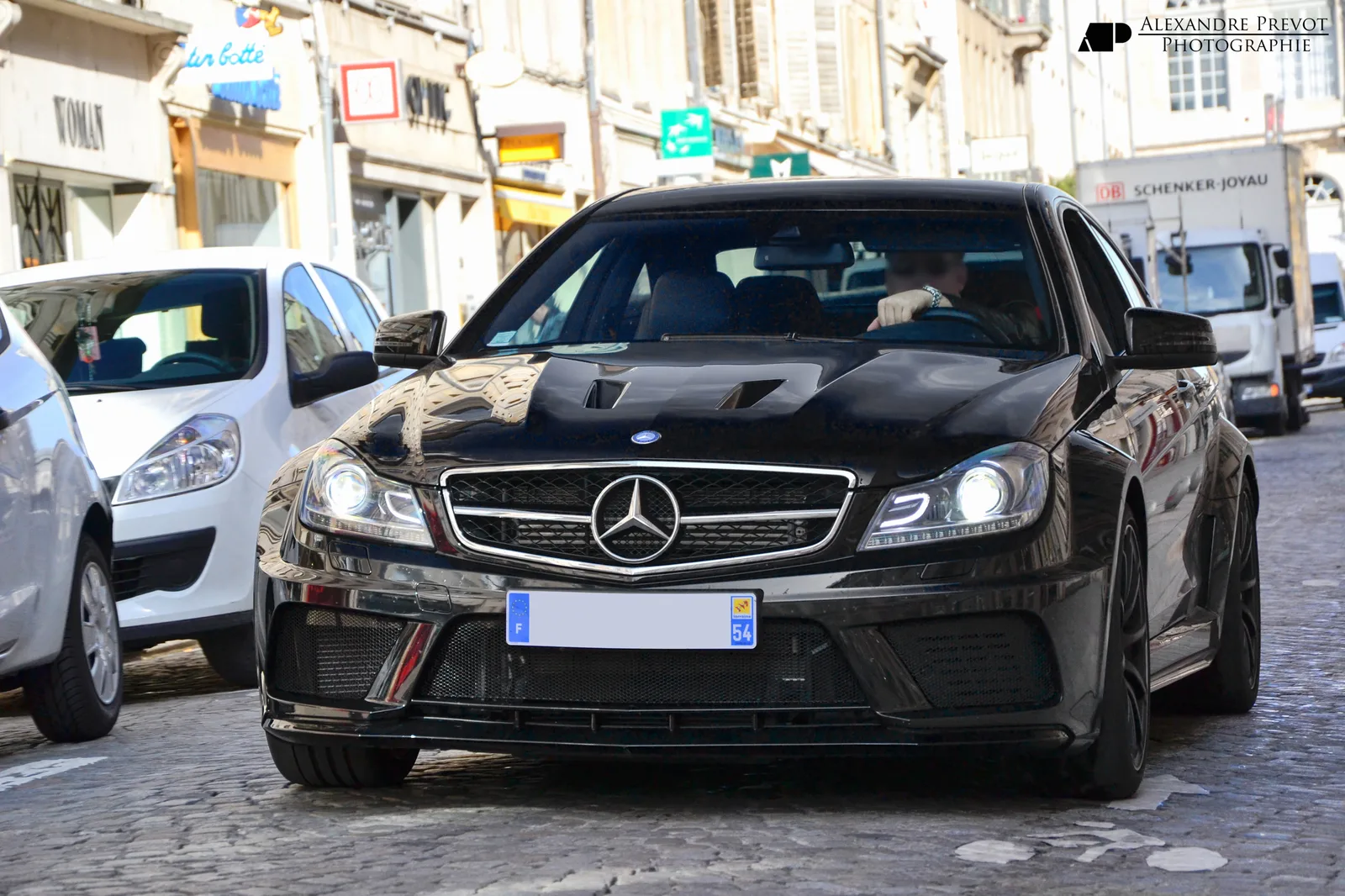 Black Mercedes-Benz C 63 AMG Coupe Black Series driving on a city street, head-on view