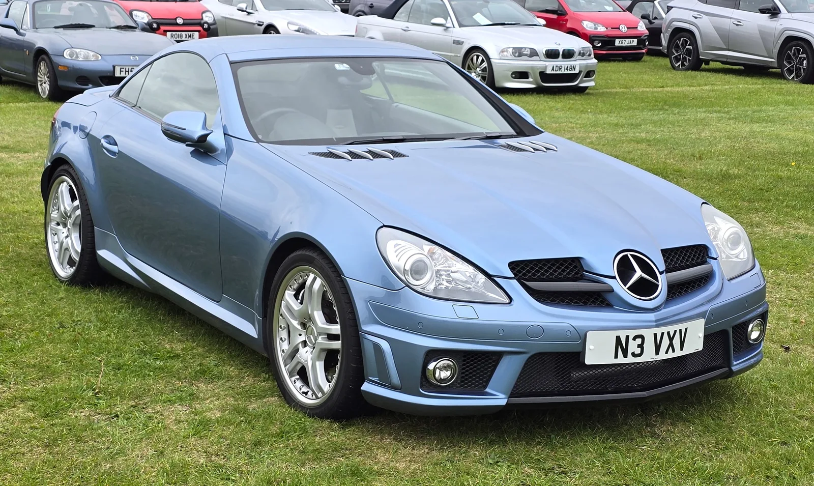 Blue Mercedes-Benz SLK 55 AMG Black Series parked on grass, front three-quarter view
