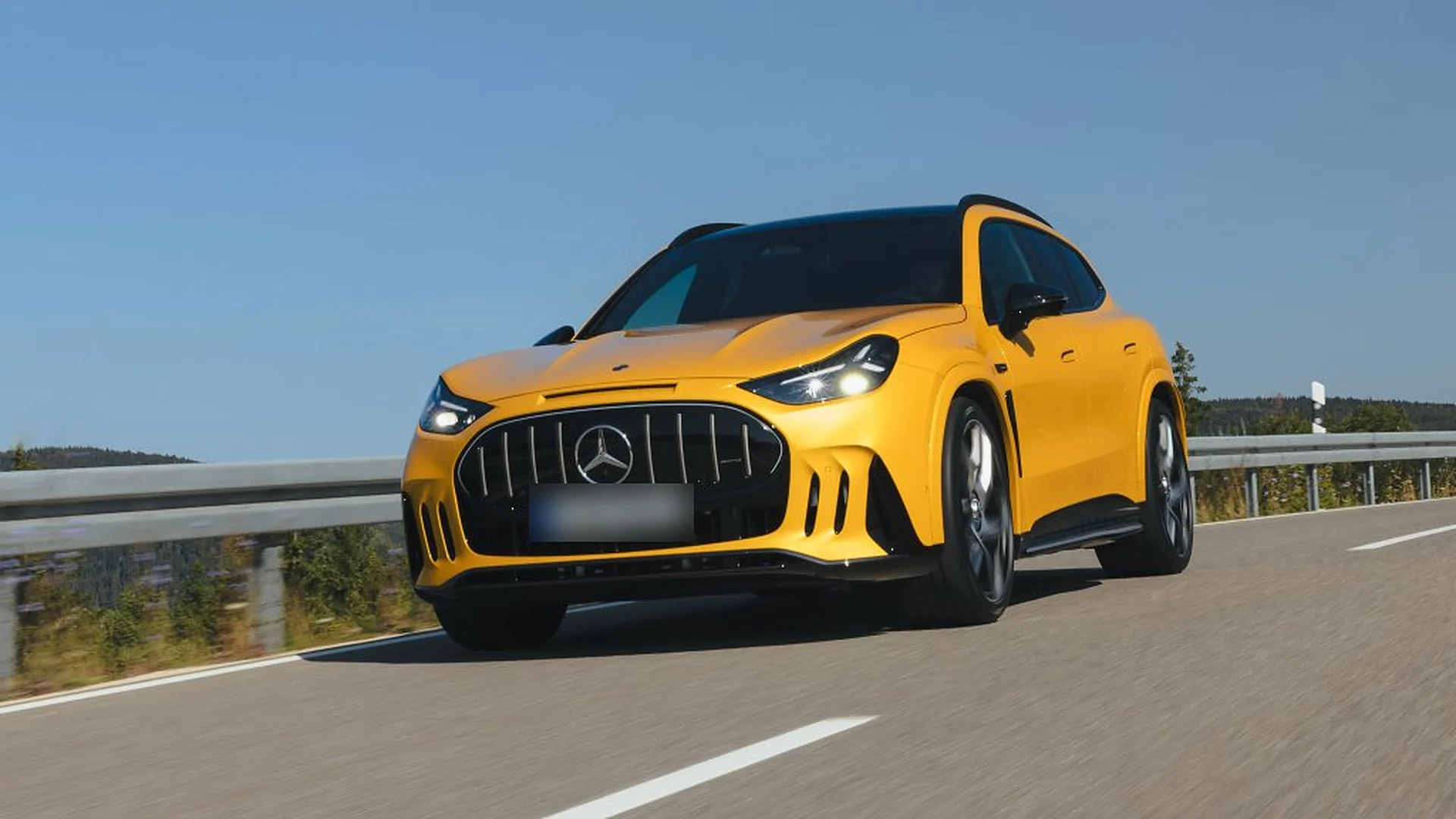 Yellow Mercedes-AMG GT SUV driving towards the camera with illuminated grille bars and slim LED headlights