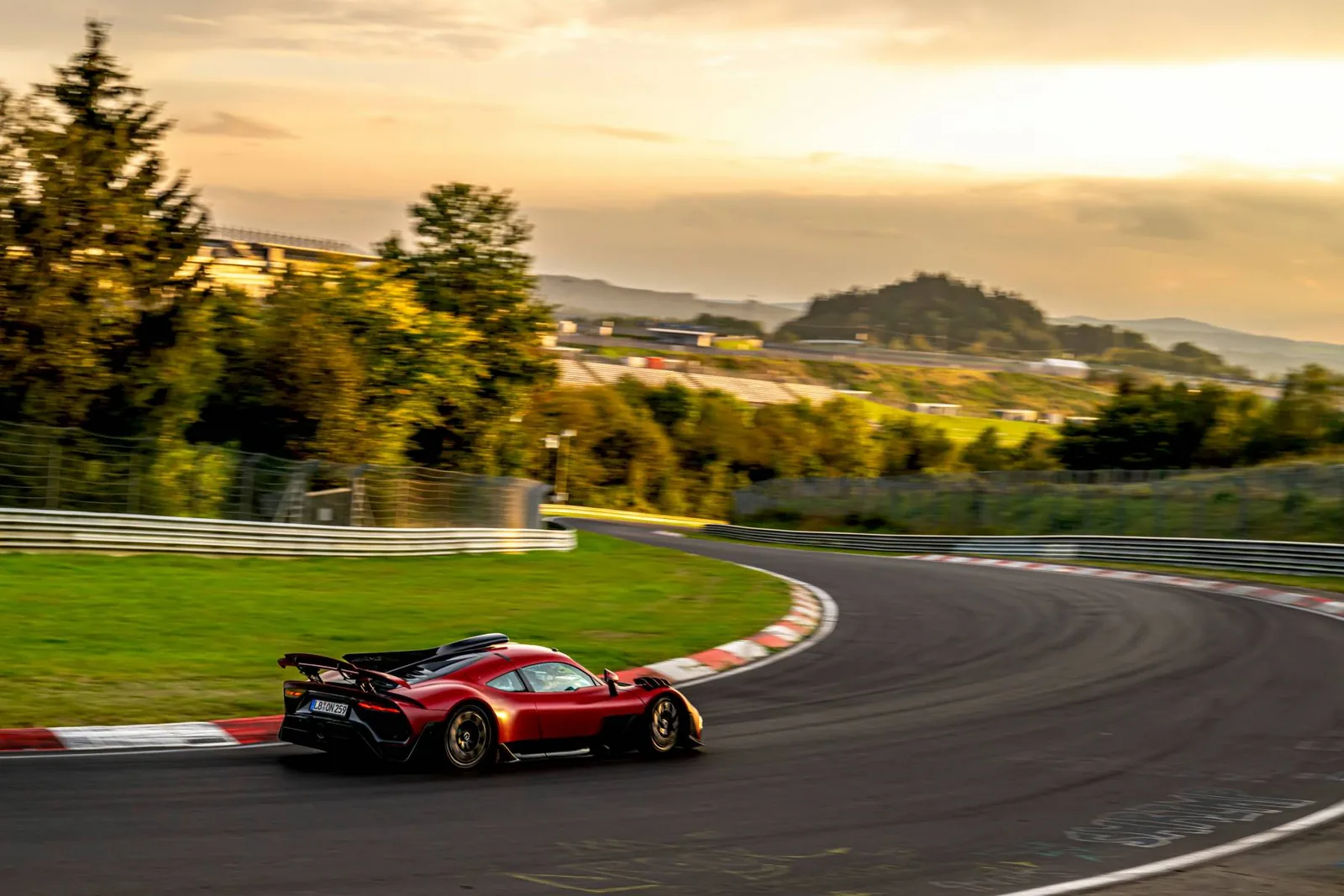 Rear view of the Mercedes-AMG ONE cornering on the Nürburgring Nordschleife at sunset with rear wing deployed